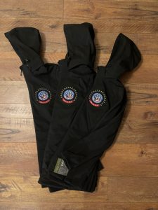 Black hooded windbreaker jackets with embroidered patriotic What A Ride motorcycle patch