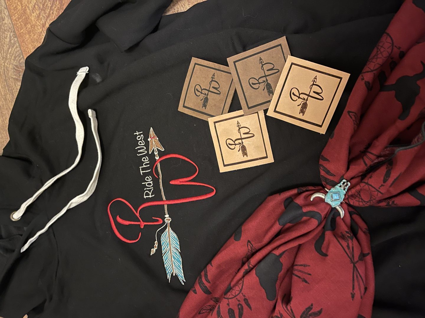 Black hoodie with embroidered Ride The West arrow and feathers logo with laser engraved leather patches