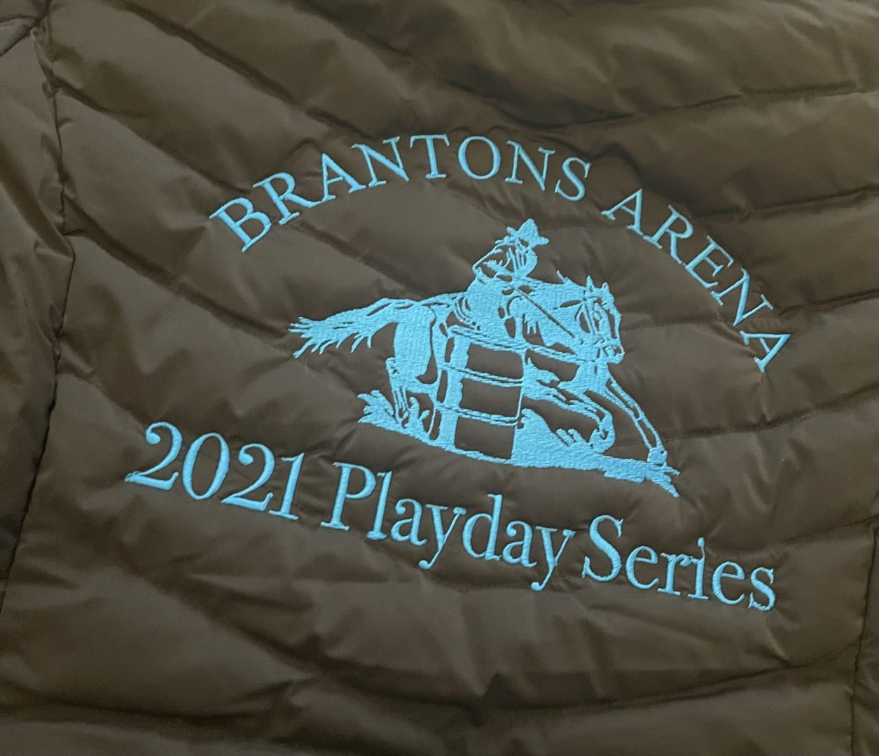 Brown quilted jacket with turquoise embroidered Brantons Arena barrel racing Playday Series logo
