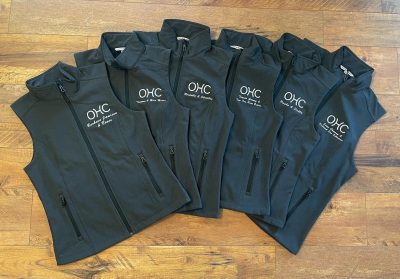 Gray softshell vests with embroidered OHC Oregon Horse Center logo and personalized rider names