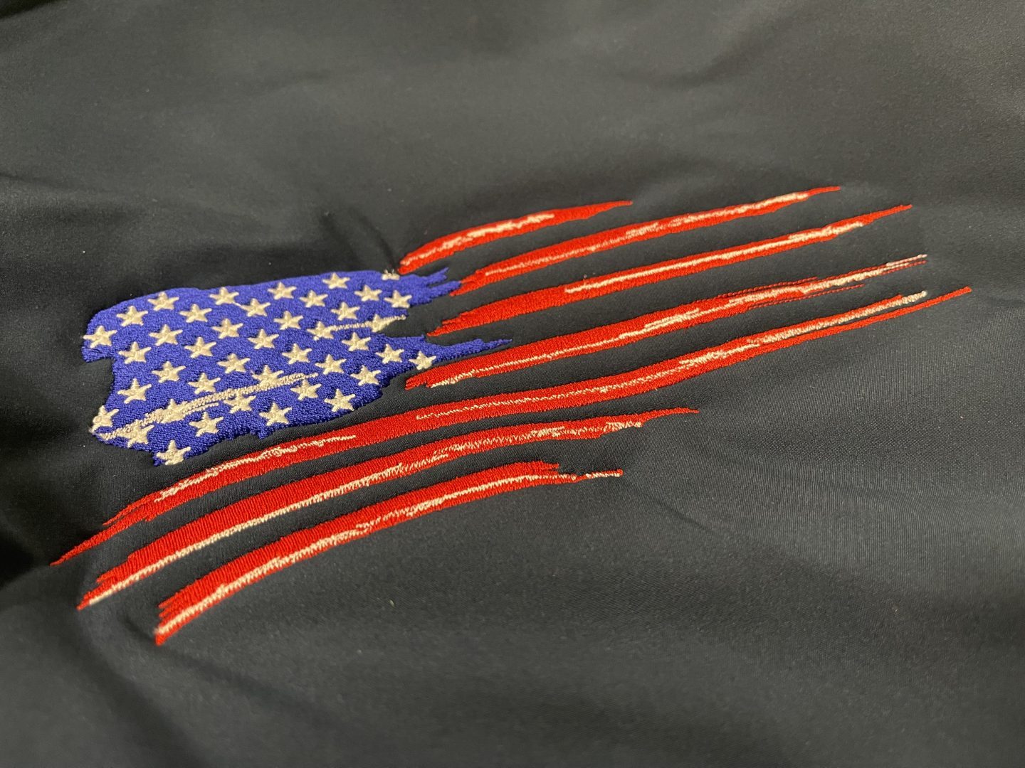 Embroidered tattered American flag patriotic design on black fabric with stars and stripes