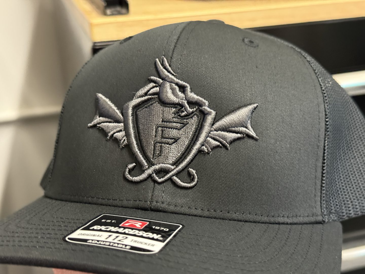 Black Richardson trucker hat with 3D puff embroidered dragon and shield F logo in charcoal gray