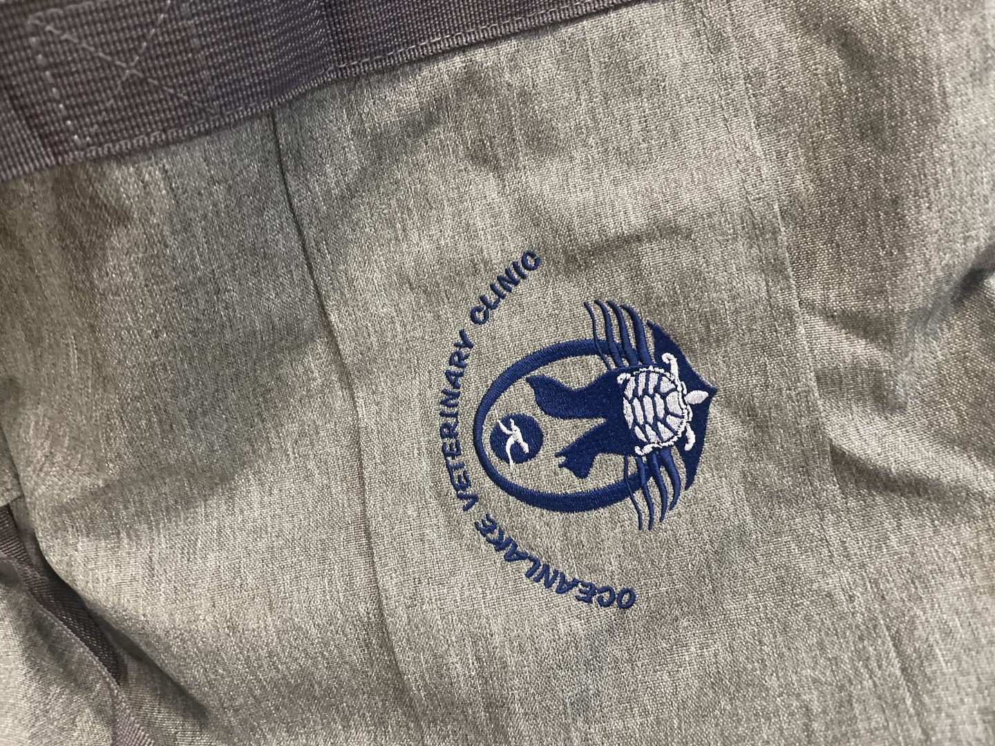 Gray garment with embroidered Ocean Lake Veterinary Clinic logo featuring cat turtle and dog