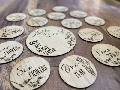Laser engraved wooden baby milestone marker discs with Hello World and monthly markers with floral designs