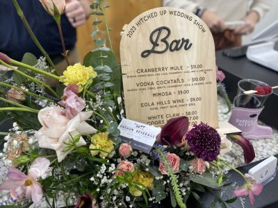 Laser engraved wooden wedding bar menu sign with cocktail prices and floral arrangement