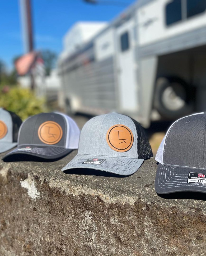 Richardson trucker hats with round leather patches featuring ranch cattle brand logo by horse trailer