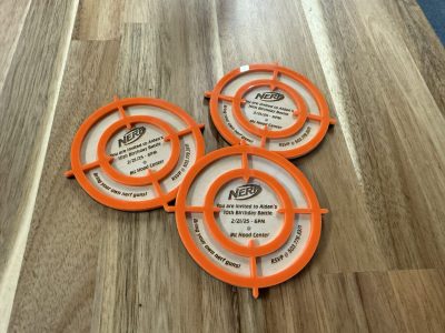 Laser cut wooden Nerf birthday party invitations with orange target crosshair frame design personalized