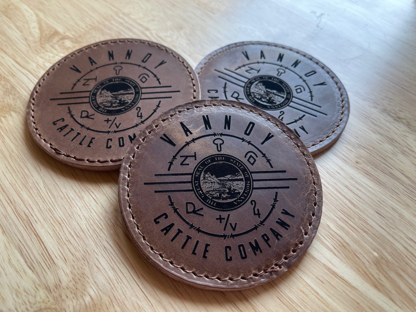 Round laser engraved leather coasters Vannoy Cattle Company with Montana seal and ranch brand symbols
