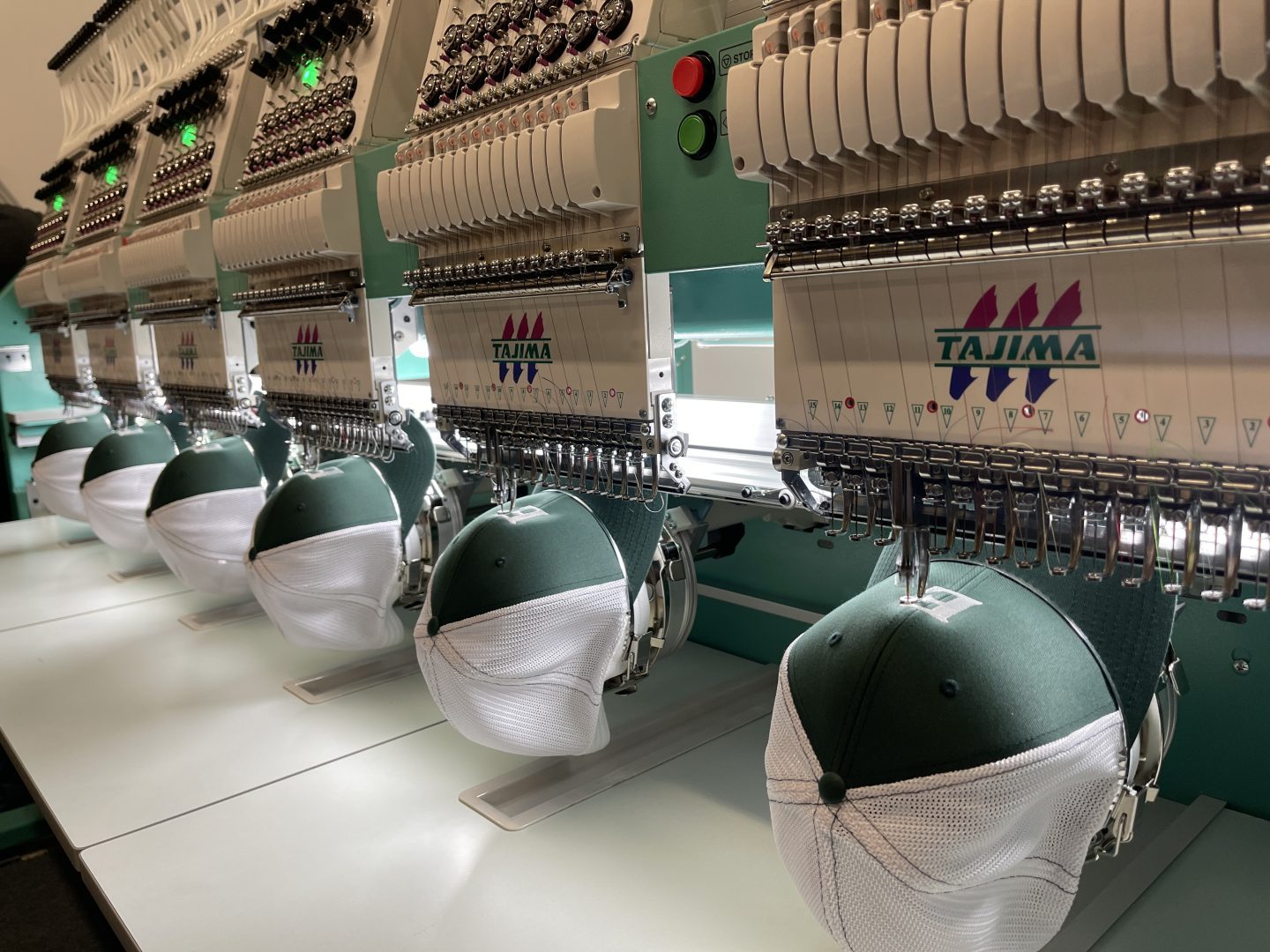 Tajima multi-head embroidery machine with green white trucker hats in production commercial equipment